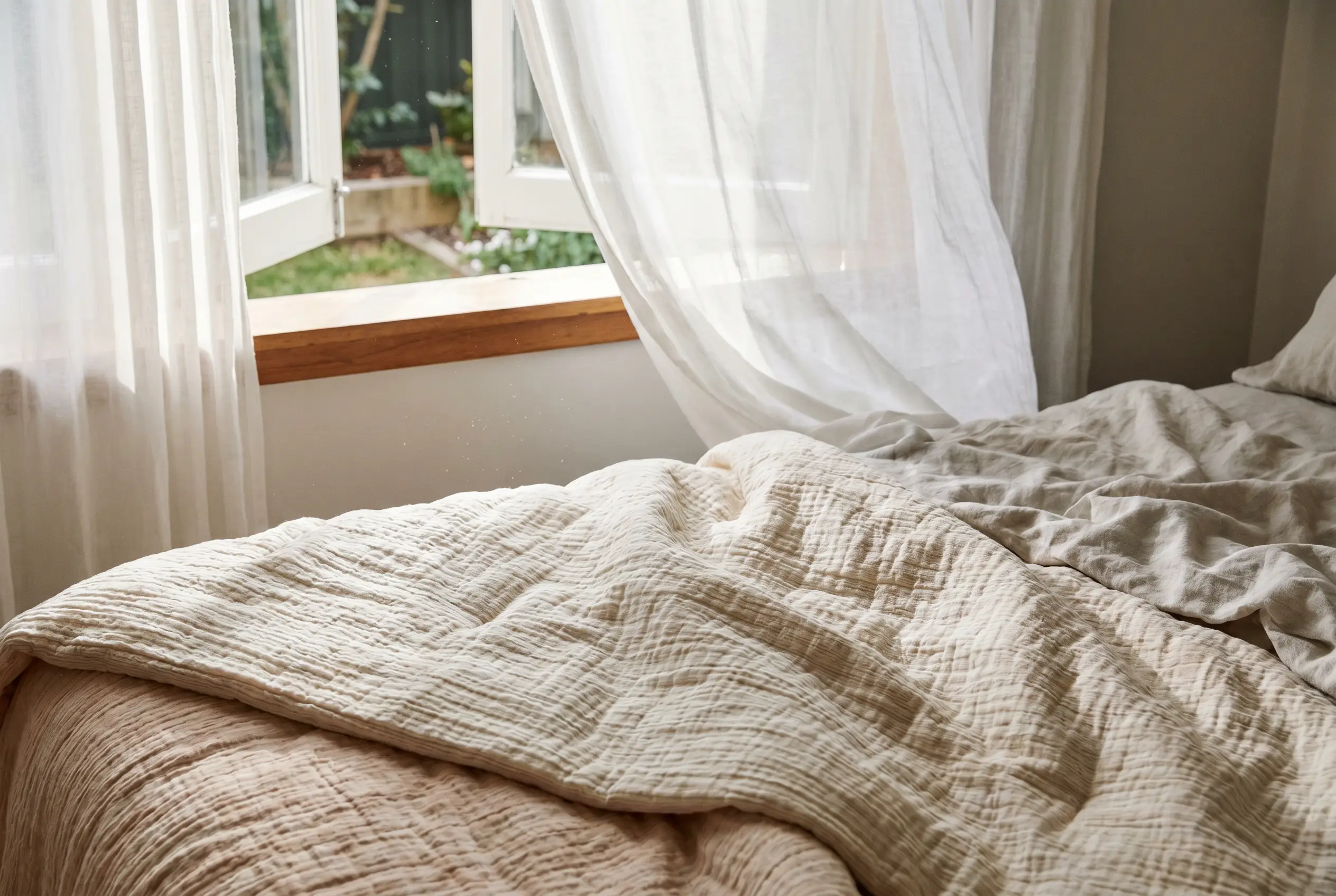 A lightweight cooling comforter with a crisp weave near an open window